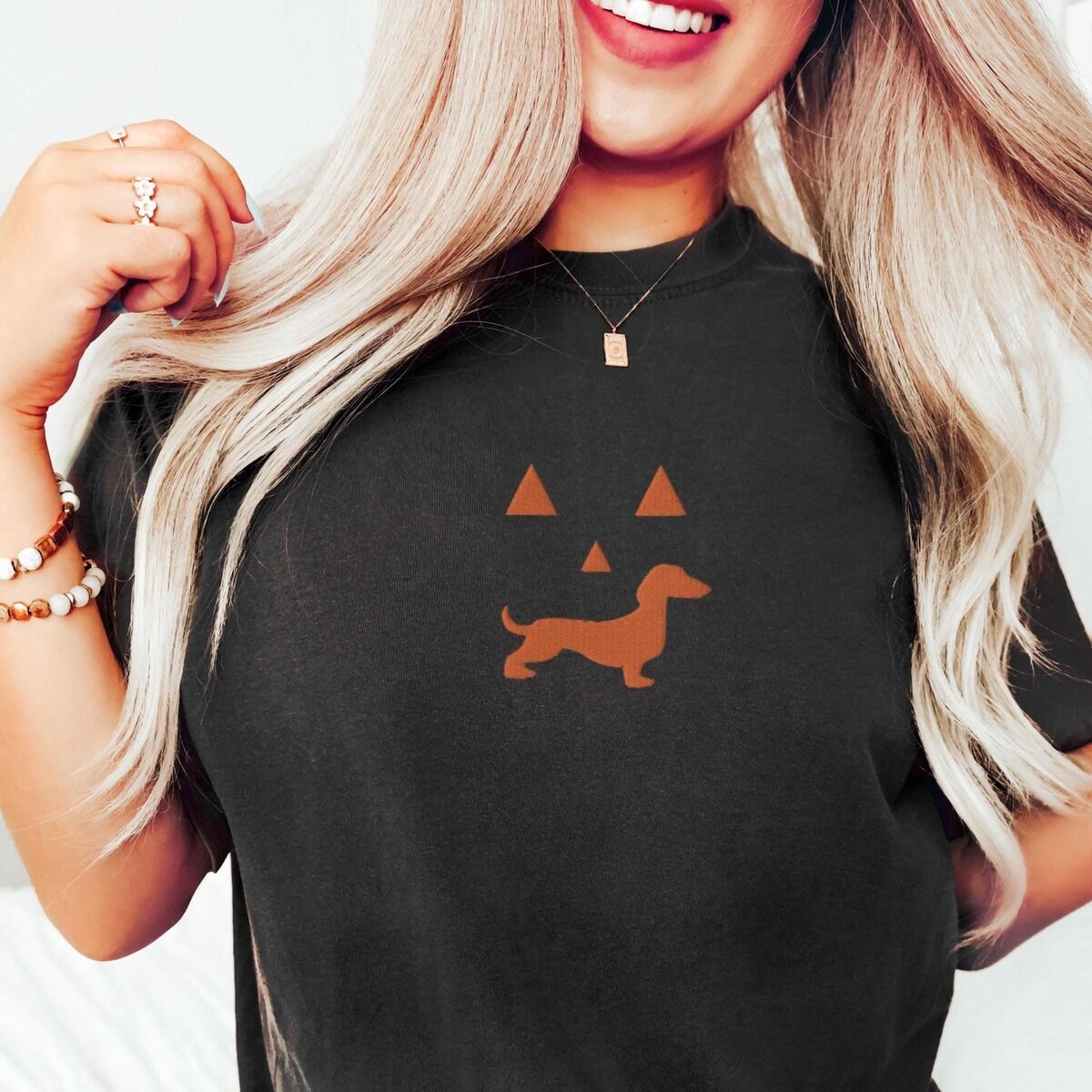 Dachshund Jack-o'-Lantern Shirt – Black Woman in a Black T-shirt embroidered across the chest with an orange dachshund jack-o'-lantern face
