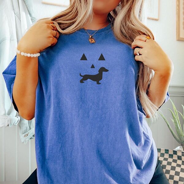 Woman in a Flo Blue T-shirt embroidered across the chest with a black dachshund jack-o'-lantern face
