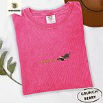 Crunchberry Comfort Colors T-shirt embroidered with a black and tan dachshund in a Santa hat bowing down to sniff a string of gold jingle bells