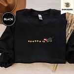 Black crewneck sweatshirt with a brown felt hat and dried bunny tail grass, embroidered with a black and tan dachshund in a Santa hat bowing down to sniff a string of six gold jingle bells