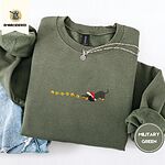 Military Green crewneck sweatshirt folded with light jeans and a silver chain necklace, embroidered with a black and tan dachshund in a Santa hat bowing down to sniff a string of six gold jingle bells