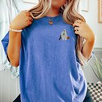 Woman in a Flo Blue T-shirt embroidered on the left chest with a ghost sipping an iced matcha, a black and tan dachshund and a jack-o'-lantern pail