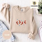 Sand crewneck sweatshirt folded with denim shorts, white sneakers and a potted plant, embroidered with four red dachshunds in red Fair Isle sweaters tumbling among light blue snowflakes