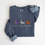 Denim crewneck sweatshirt laid flat on white, embroidered with three dachshunds dressed as a witch, a mummy and a pumpkin with bats overhead, above the words HAPPY HALLOWEENIE