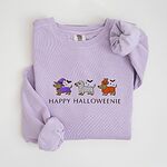 Orchid crewneck sweatshirt laid flat on white, embroidered with three dachshunds dressed as a witch, a mummy and a pumpkin with bats overhead, above the words HAPPY HALLOWEENIE