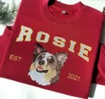 Dog face Christmas sweatshirt in maroon with an embroidered Australian shepherd portrait, the name ROSIE in white varsity letters and EST 2021