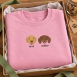 Light Pink sweatshirt with an embroidered yellow Labrador and dachshund named Bear and Peanut, folded in a kraft gift box