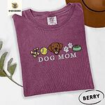 Berry Comfort Colors T-shirt embroidered with a row of dog treats, a tennis ball, a chocolate Lab face, paw prints and a food bowl above the words DOG MOM