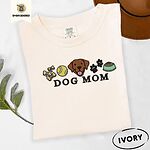 Ivory Comfort Colors T-shirt embroidered with a row of dog treats, a tennis ball, a chocolate Lab face, paw prints and a food bowl above the words DOG MOM