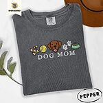 Pepper Comfort Colors T-shirt embroidered with a row of dog treats, a tennis ball, a chocolate Lab face, paw prints and a food bowl above the words DOG MOM