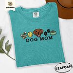 Seafoam Comfort Colors T-shirt embroidered with a row of dog treats, a tennis ball, a chocolate Lab face, paw prints and a food bowl above the words DOG MOM