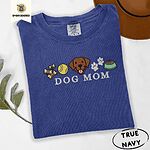 True Navy Comfort Colors T-shirt embroidered with a row of dog treats, a tennis ball, a chocolate Lab face, paw prints and a food bowl above the words DOG MOM