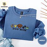 Indigo Blue crewneck sweatshirt folded with light jeans and dried twigs, embroidered with a row of dog treats, a tennis ball, a chocolate Lab face, paw prints and a food bowl above the words DOG MOM