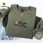 Military Green crewneck sweatshirt folded with light jeans and a silver chain necklace, embroidered with a row of dog treats, a tennis ball, a chocolate Lab face, paw prints and a food bowl above the words DOG MOM