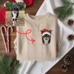 Sand pullover with an embroidered chihuahua portrait in a Santa hat with antlers, made from the dog photo shown beside it