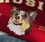 Angled view of dense thread embroidery showing a dog face portrait under varsity name lettering