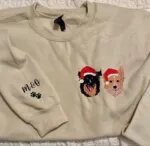 Sand sweatshirt with two embroidered dogs in Santa hats on the chest and M&O initials with paw prints on the sleeve
