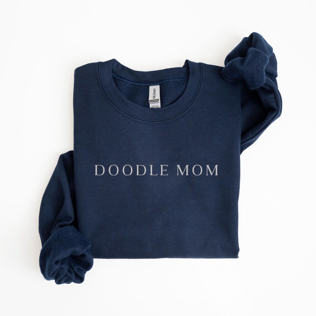 Doodle Mom Crewneck – Navy Navy crewneck sweatshirt laid flat with a rolled cuff, embroidered with DOODLE MOM in light serif capitals across the chest