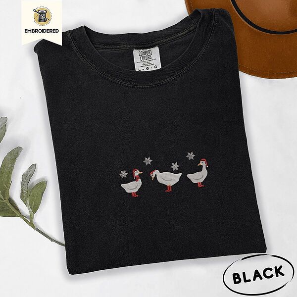 Black Comfort Colors T-shirt embroidered with three white ducks in Santa hats and red rain boots under silver snowflakes