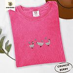 Crunchberry Comfort Colors T-shirt embroidered with three white ducks in Santa hats and red rain boots under silver snowflakes