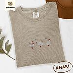 Khaki Comfort Colors T-shirt embroidered with three white ducks in Santa hats and red rain boots under silver snowflakes