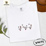 White Comfort Colors T-shirt embroidered with three white ducks in Santa hats and red rain boots under silver snowflakes