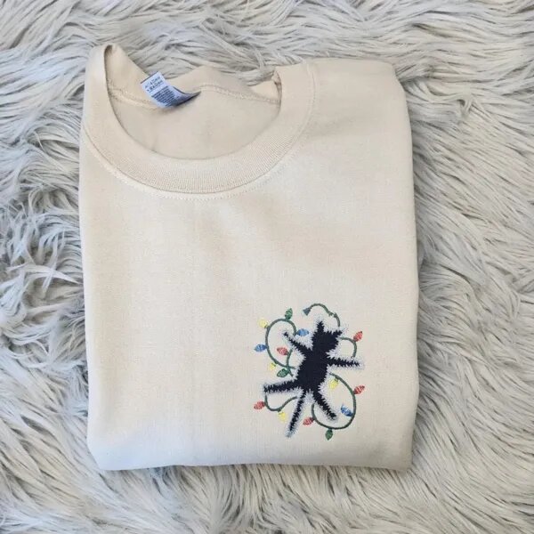 Electrocuted cat sweatshirt in Sand with a black cat tangled in Christmas lights embroidered on the left chest