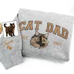 Sport grey sweatshirt with copper CAT DAD lettering, an embroidered tortoiseshell cat face, EST. 2025 and the name Taro with paw prints on the sleeve