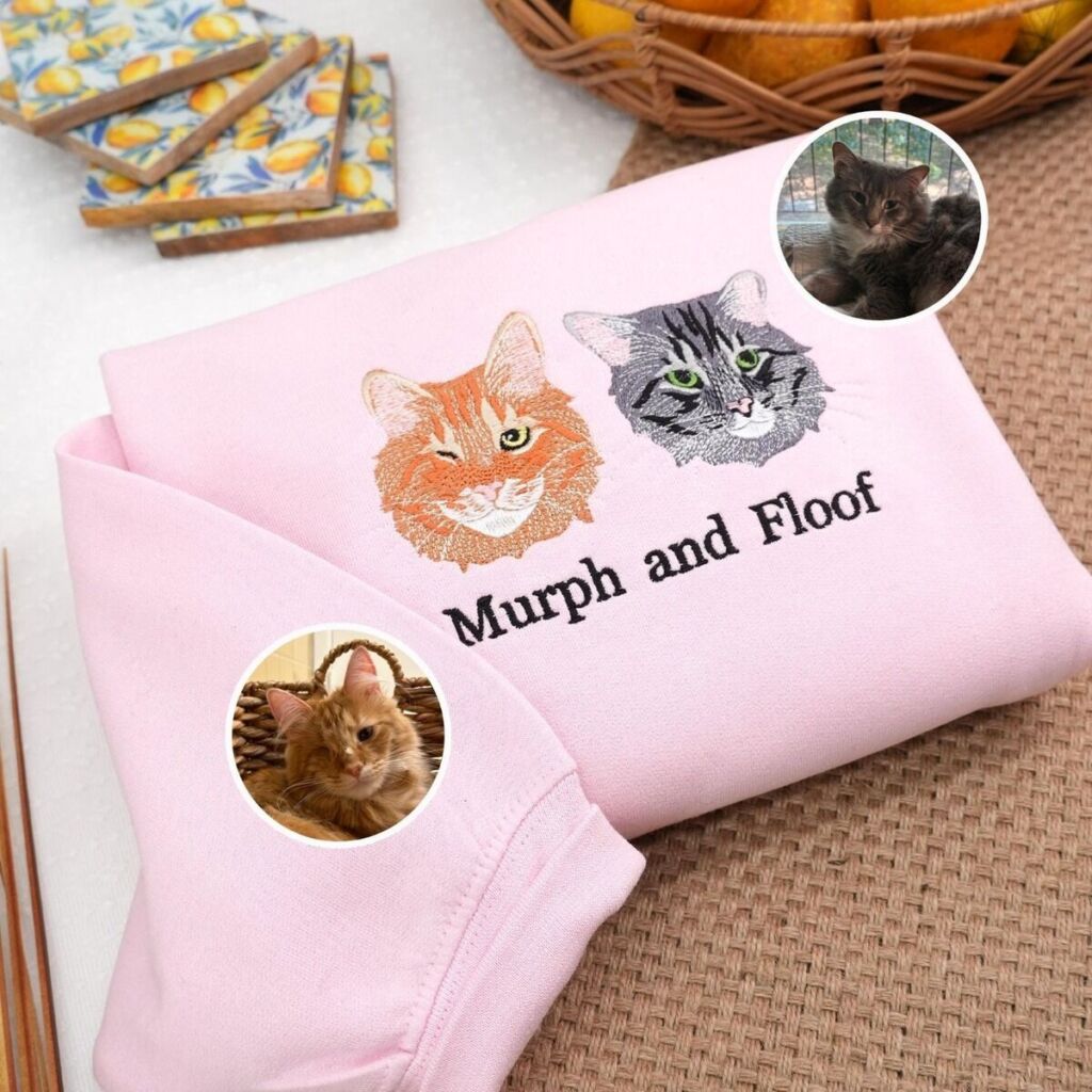 Light pink sweatshirt with an orange cat and a gray tabby embroidered side by side above the text Murph and Floof, with the original photos