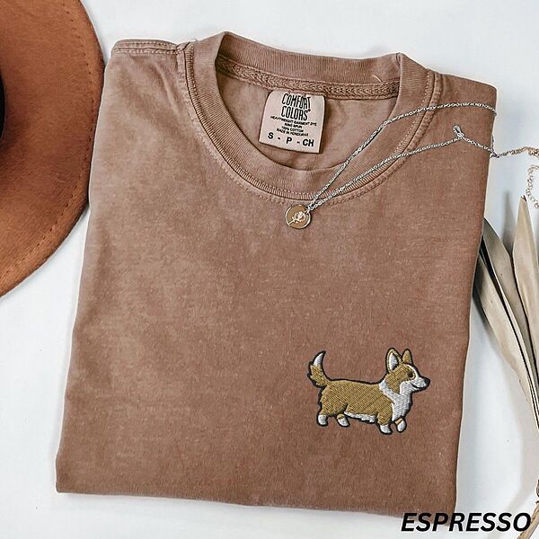 Espresso Comfort Colors T-shirt embroidered with a cute cartoon corgi in golden tan and white trotting on the left chest