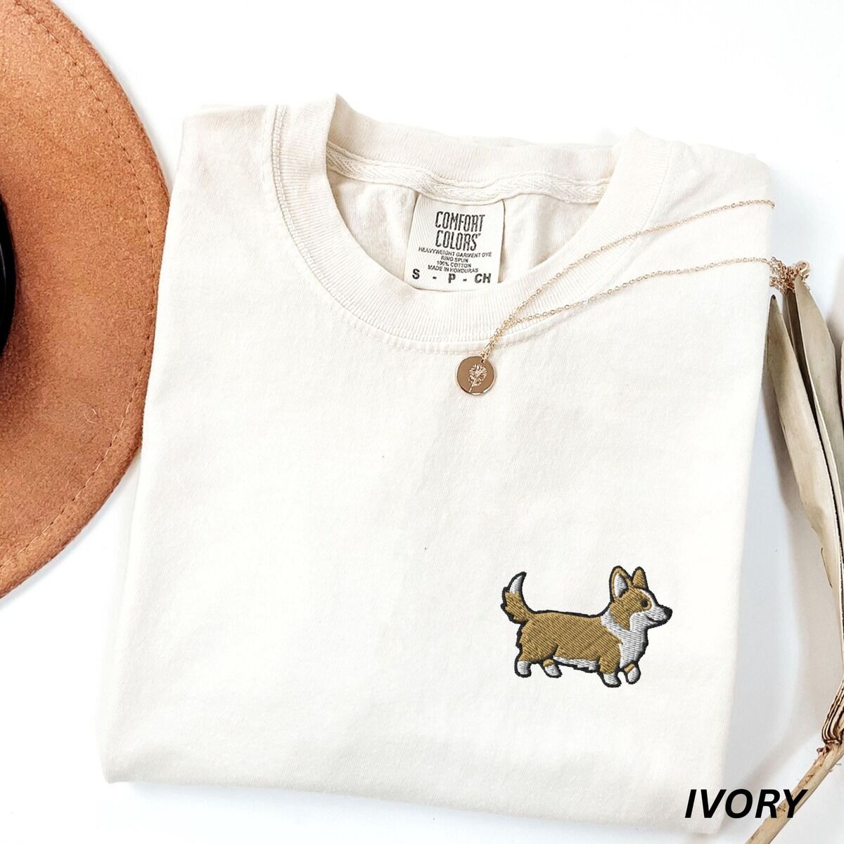 Embroidered Corgi Shirt – Ivory Ivory Comfort Colors T-shirt embroidered with a cute cartoon corgi in golden tan and white trotting on the left chest