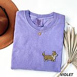 Violet Comfort Colors T-shirt embroidered with a cute cartoon corgi in golden tan and white trotting on the left chest