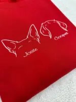Close-up of white thread dog ear embroidery and the name Josie on a red sweatshirt
