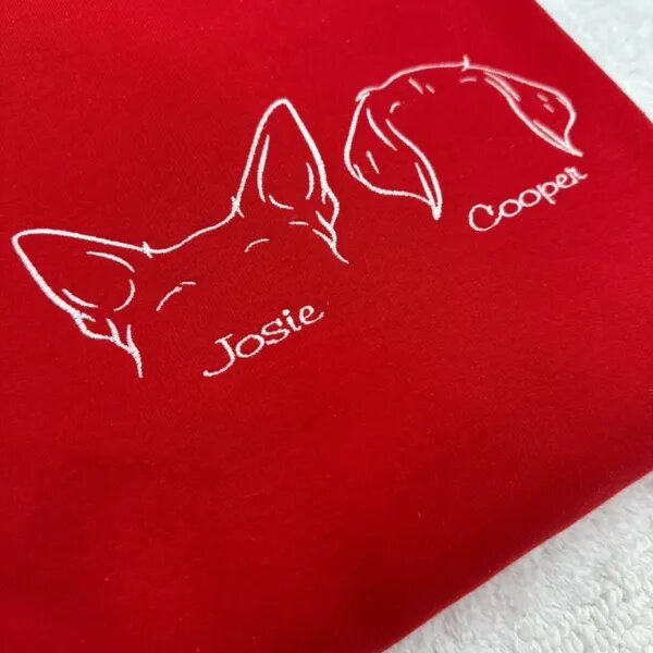 Close-up of white thread dog ear embroidery and the name Josie on a red sweatshirt