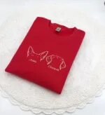 Red embroidered dog ears sweatshirt with white outline ears and the names Josie and Cooper