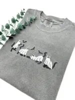 Angled view of the embroidered ghost cats and bats on a pepper charcoal tee