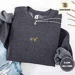 Dark Heather crewneck sweatshirt folded with ripped jeans and a silver chain necklace, embroidered with a mini apricot goldendoodle trotting in a gold collar with its tongue out, in the center of the chest