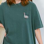 Woman in a Blue Spruce T-shirt embroidered with a small white goose and the word silly on the left chest
