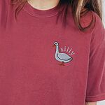 Woman in a Crimson T-shirt embroidered with a white goose and the word silly in white thread
