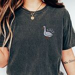 Woman wearing a gold necklace and a Pepper T-shirt embroidered with a white goose and the word silly