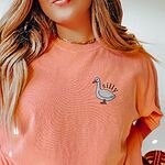 Smiling woman in a Terracotta T-shirt embroidered with a white goose and the word silly on the left chest