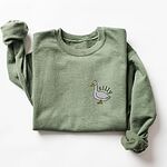 Military Green crewneck sweatshirt laid flat with a rolled sleeve, embroidered with a little white goose with the word silly arched over its back on the left chest