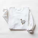 White crewneck sweatshirt laid flat with a rolled cuff, embroidered with a little white goose with the word silly arched over its back on the left chest