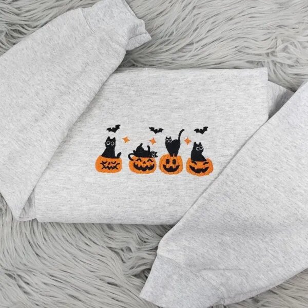 Embroidered Halloween crewneck in light heather grey with four black cats in jack-o'-lanterns across the chest