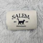 Embroidered Salem sweatshirt in Sand with SALEM, a black cat silhouette, Est. 1626 and Massachusetts stitched in black thread