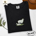 Black Comfort Colors T-shirt embroidered with a woolly white ewe standing over her lamb resting on green grass