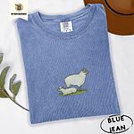 Blue Jean Comfort Colors T-shirt embroidered with a woolly white ewe standing over her lamb resting on green grass