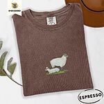 Espresso Comfort Colors T-shirt embroidered with a woolly white ewe standing over her lamb resting on green grass