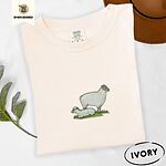Ivory Comfort Colors T-shirt embroidered with a woolly white ewe standing over her lamb resting on green grass