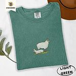 Light Green Comfort Colors T-shirt embroidered with a woolly white ewe standing over her lamb resting on green grass